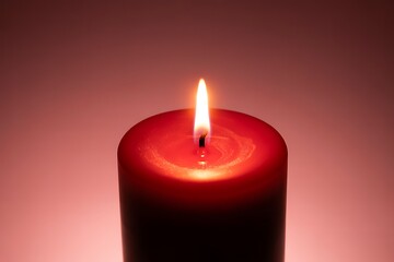 A solitary red candle burns brightly against a soft, warm background