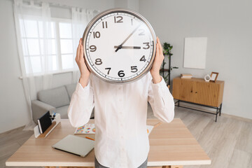 Businesswoman with wall clock in office