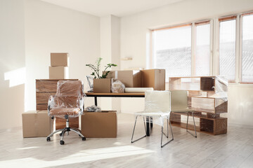 Fototapeta premium Wrapped furniture with stretch film and boxes in office on moving day