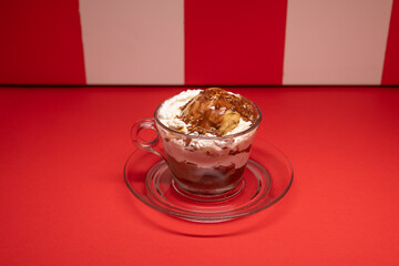 Layered chocolate dessert served in glass cup over red stripes.