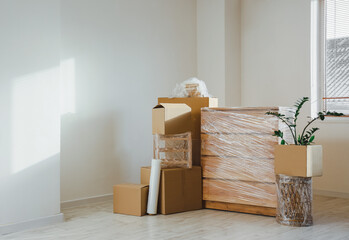 Wrapped furniture with stretch film and boxes in room on moving day