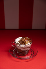 Layered chocolate dessert served in glass cup over red stripes.