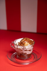 Layered chocolate dessert served in glass cup over red stripes.