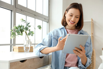 Smiling young woman using tablet computer at home