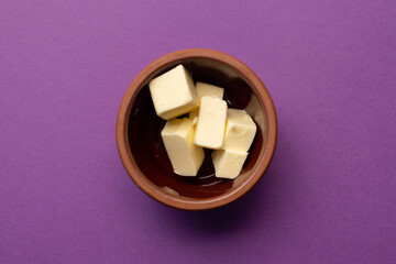 Butter cubes stacked in terracotta clay bowl.