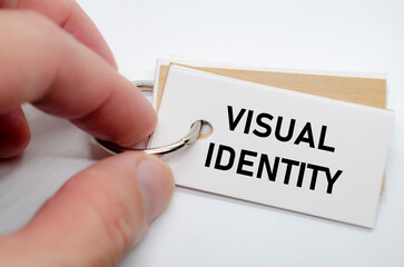 Visual identity concept presented on white notepad with hand holding it in clean workspace.