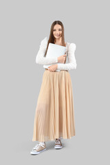 Young woman with laptop on light background