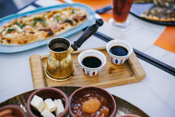 Traditional Lebanese breakfast with coffee, mezze, and bread on table.

