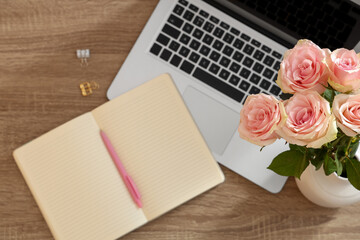 Modern laptop with blank notebook and beautiful flowers on wooden table, top view
