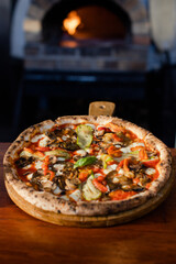 Rustic vegetable pizza served on checkered cloth in outdoor setting.
