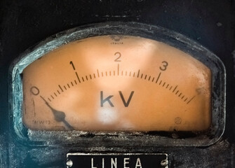 Vintage kilovolt electrical meter gauge with warm amber lighting. Classic industrial instrument perfect for heritage and technical content.
