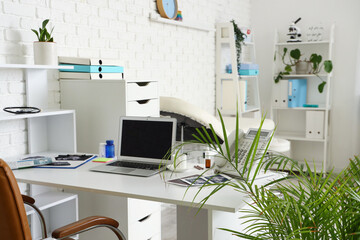 Doctor's workplace with blank laptop and telephone in medical office