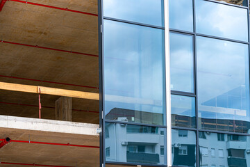 Installation of unitized glass curtain wall panel on modern concrete building under construction