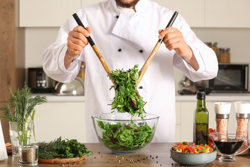 Male chef stirring vegetable salad at table in kitchen