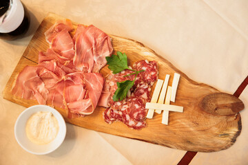 tagliere di legno con affettati misti e fette di formaggio, su un tavolo apparecchiato, visto...
