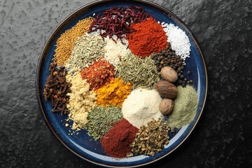 Different aromatic spices on dark textured table, top view