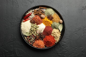 Different aromatic spices on dark textured table, top view
