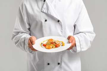 Male chef with tasty pasta on light background, closeup