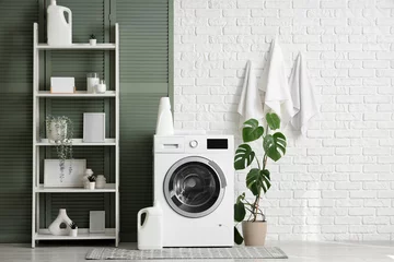 Fotobehang Modern washing machine with shelving unit, houseplant and detergents near white brick wall in laundry room © Pixel-Shot