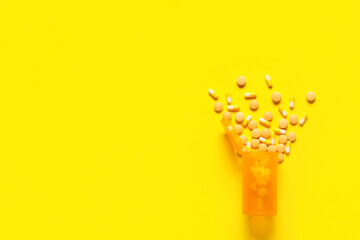 Jar with different pills on yellow background