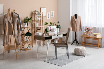 Interior of atelier with tailor's workplace, clothes rack and mannequin