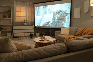 Interior of stylish living room with grey sofas, coffee table and modern projector screen