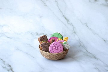 Colorful gingerbread cookies in a woven basket on marble background. Sheep and mosque shapes, perfect for celebrations Eid al-Adha, sacrifice feast,