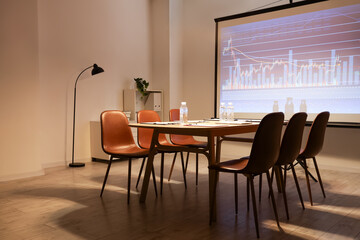 Interior of modern conference hall with table, chairs and projector screen