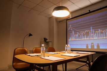 Interior of modern conference hall with table, chairs and projector screen