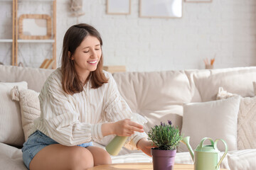 Young woman spraying water onto lavender flowers at home