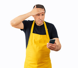 Man wearing yellow apron texting using smartphone over isolated white background stressed with hand...
