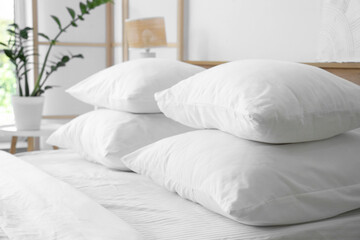 Soft white pillows on bed in light room