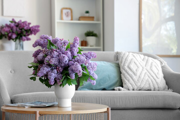 Vase with beautiful lilac flowers and magazines on table in living room