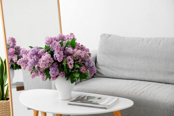 Vase with beautiful lilac flowers and magazine on table in living room