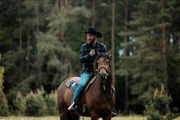 cowboy man in hat riding horse across meadow	