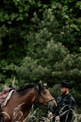 cowboy man with red beard in hat with horse close-up, friendship with animal