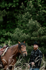 cowboy man with red beard in hat with horse close-up, friendship with animal