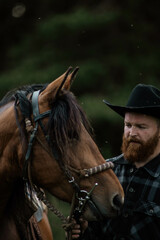 cowboy man with red beard in hat with horse close-up, friendship with animal
