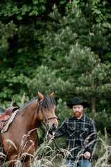 cowboy man with red beard in hat with horse close-up, friendship with animal