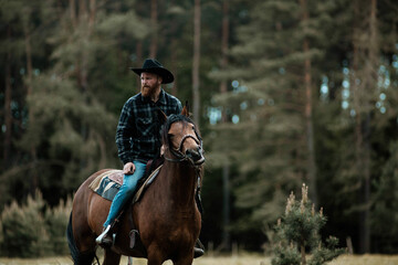 cowboy man in hat riding horse across meadow	