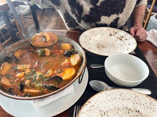 Rustic seafood and potato stew served hot, European dining, cozy meal celebration, inviting winter...