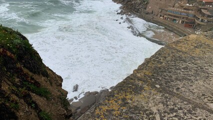 Cliffside view overlooking ocean waves crashing against rugged coastline, ideal for travel...