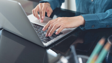 Business woman hand typing, working on laptop computer at office, close up. Businesswoman using laptop, surfing the internet, searching the information, remote work, internet technology