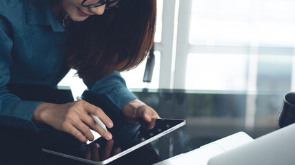 Business woman using digital tablet, reading and proofing business document, working at office. Asian smart businesswoman working on tablet pc with laptop on table office, close up, business plan