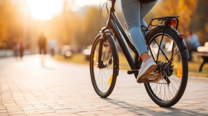 Obraz premium Person Riding Bicycle Along Paved Pathway in Park During Autumn Sunset with Warm Light