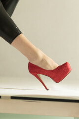 A closeup view of a shimmering red stiletto shoe, positioned elegantly, showcasing its stunning...