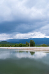 Obraz premium Lake under Ominous Clouds with Mountain Backdrop
