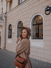 Beautiful young woman in hat and coat walking around european city