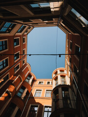 Low angle view of residential building courtyard featuring orange facade and clear blue sky,...