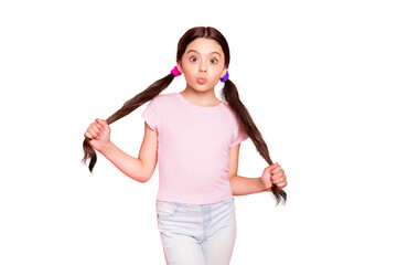 Portrait of cute child touching pigtails making faces dressed white t-shirt pants isolated over pink background